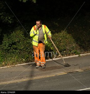 DFA60R A local authority council direct labour worker leaning on his spade shovel smoking a cigarette UK