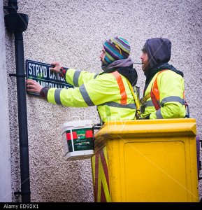 ED92X1 Two Local authority (Ceredigion County Council) direct labour employees workers  in a 'cherry picker' replacing the sign on Cambrian Street , Aberystwyth, with new versions with 'heritage' typeface, Wales UK